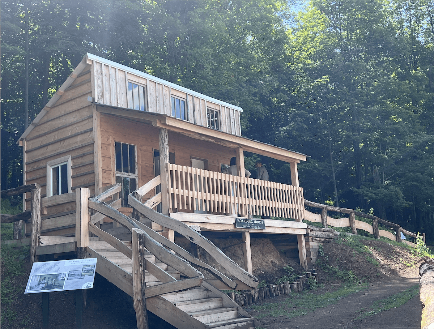 Wooden boarding house with porch and stairs.